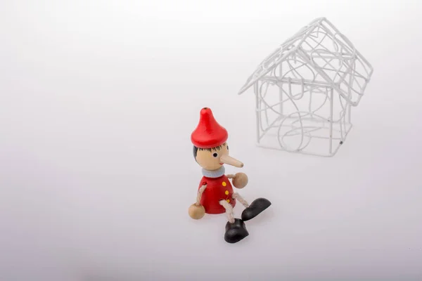 Pinokio Siedzi Obok Modelowego Domu — Zdjęcie stockowe