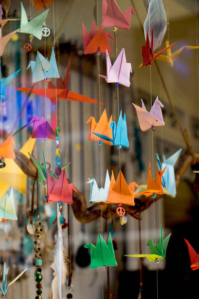 Colorful paper origami birds tied to strings hanging in air