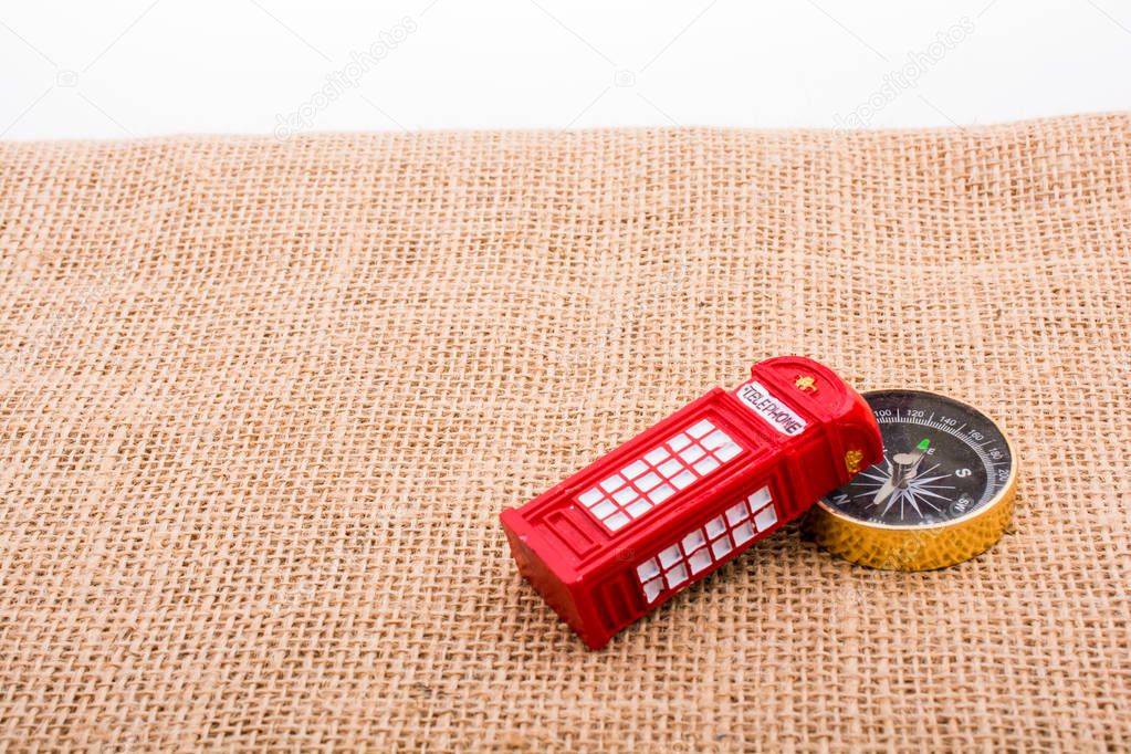 Compass and red color phone booth on canvas background