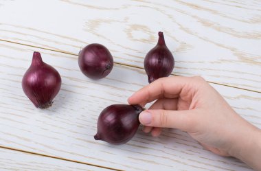 Tüm kırmızı soğan soğanları kahverengi ve ahşap arka planda