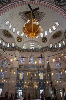 Büyük bir camide dairesel avizenin üzerindeki parlak lambalar.