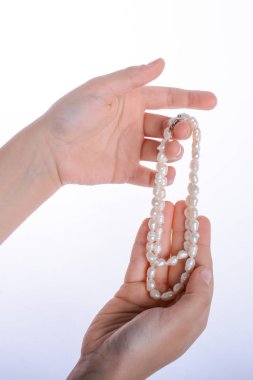 Bir inci kolye beyaz bir arka plan üzerinde tutan el