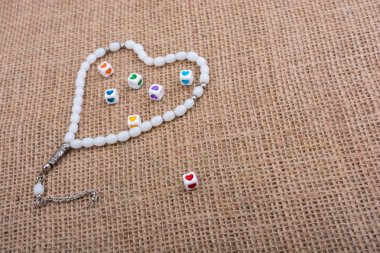 Dua eden bir boncuğun içinde ellerinde kalp şeklinde küpler.