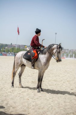 Osmanlı atlısı etnik kıyafetleriyle atına biniyor.