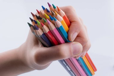 Beyaz arkaplanda el ele tutuşan renkli kalemler