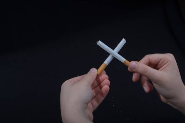 El, siyah arka planda çapraz sigara tutuyor.