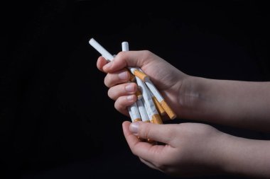 El, siyah arka planda bir paket sigara dağıtıyor.