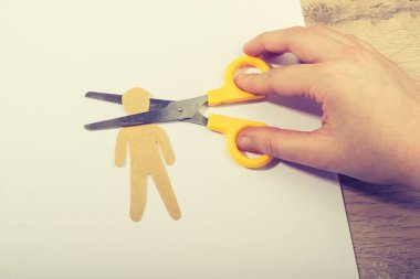 Kağıt adamın kafasını kesen makas tahta arka planda beyaz kağıt üzerinde