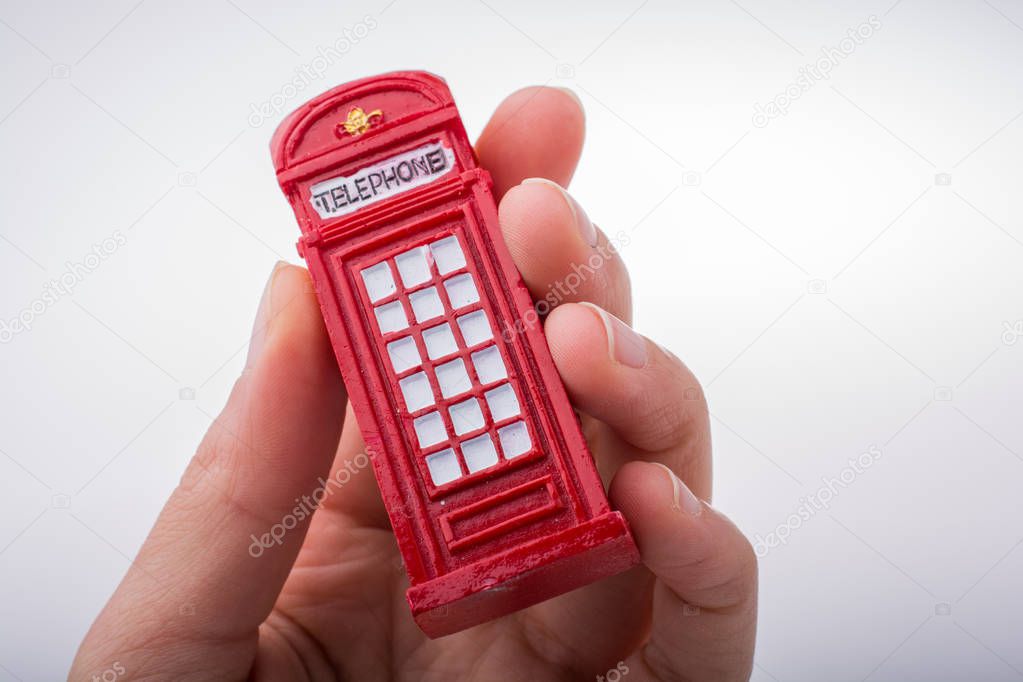 Hand holding a red color phone booth on a white background