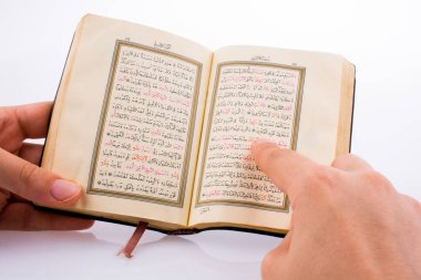 Beyaz arka planda Kuran 'ı el ele tutuşarak.