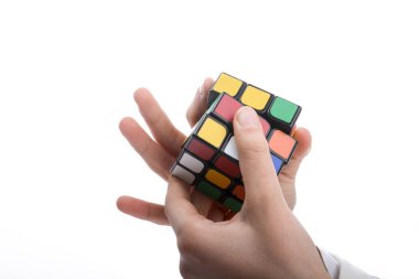 Beyaz arka planda elinde bir Rubik küpünü tutan çocuk
