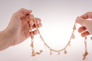 Altın renkli gülücükler Eldeki bir zincir üzerinde
