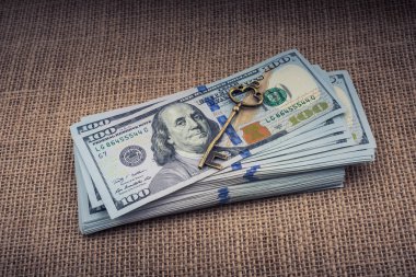 Bir tuval üzerinde geçmişe dönük anahtar ve Amerikan doları destesi