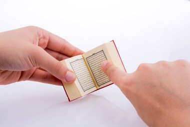 Beyaz arka planda Kuran 'ı el ele tutuşarak.