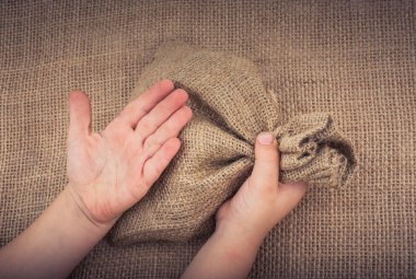 Çarşaftan yapılmış boş bir çuvalı tutan el.