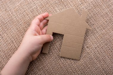 Tuvalin arka planında bir bez evi tutan el.