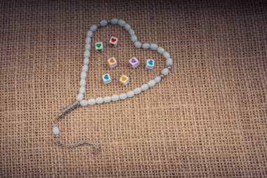 Dua eden bir boncuğun içinde ellerinde kalp şeklinde küpler.