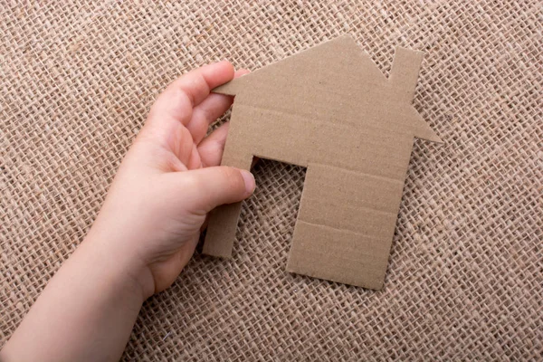 Tuvalin arka planında bir bez evi tutan el.