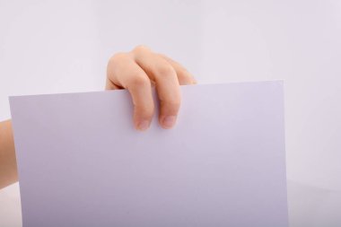 Beyaz bir arka planda beyaz bir kağıt tutuyordu.