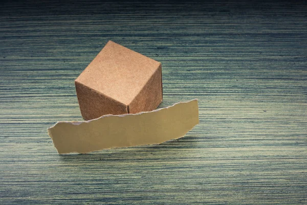 Torn paper and a paper box cube on wooden texture