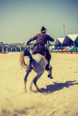 Osmanlı atlısı etnik kıyafetleriyle atına biniyor.