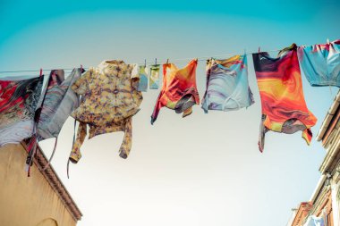 Elbiseler bir ipte sallanıyor sokakta.