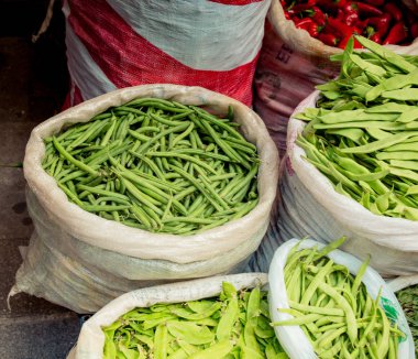 Beyaz plastik torbalarda yeşil fasulyeler.
