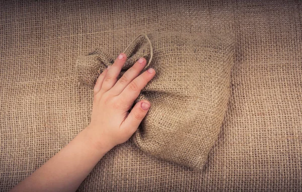 Hand holding an empty little sack made of linen