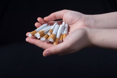 El, siyah arka planda bir paket sigara dağıtıyor.