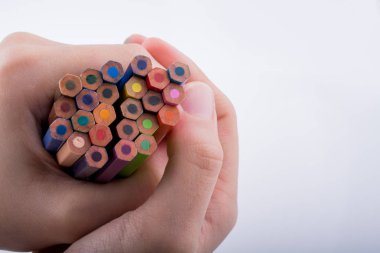 Beyaz arkaplanda el ele tutuşan renkli kalemler