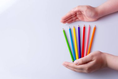 Beyaz arkaplana yerleştirilmiş el ele tutuşan kalemler