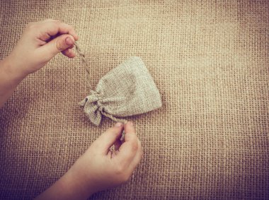 Çarşaftan yapılmış boş bir çuvalı tutan el.