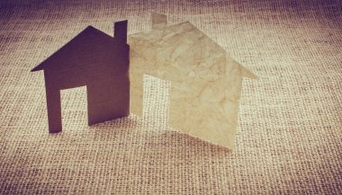 Tuvalin arka planında kağıttan yapılmış küçük bir ev şekli.