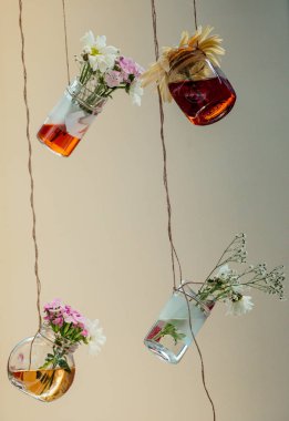 İplere asılı çiçekli bitkisel çay şişeleri