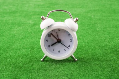 Beyaz renk çalar saat bir yeşil çim zemin üzerine