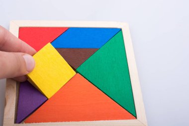 Tangram bulmacasının kayıp parçasını tutan el.