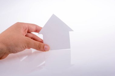 Beyaz bir arka plan üzerinde bir kağıt ev tutan el