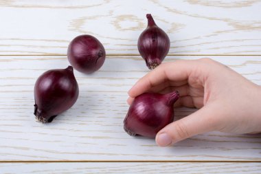 Tüm kırmızı soğan soğanları kahverengi ve ahşap arka planda