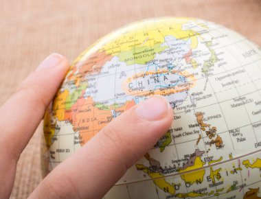 Üzerinde harita olan bir küreyi tutan el.