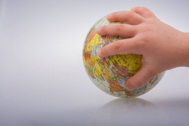 Beyaz arka planda bir küreyi tutan çocuk