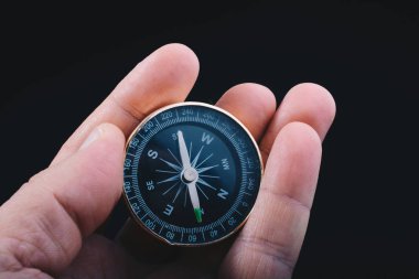 Siyah arka planda pusula tutan çocuk eli