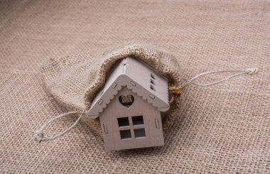 Tuvalin arka planında bir çuvalın yanındaki model ev.