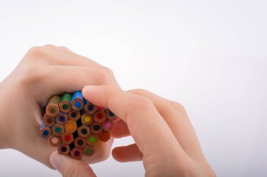 Beyaz arkaplanda el ele tutuşan renkli kalemler