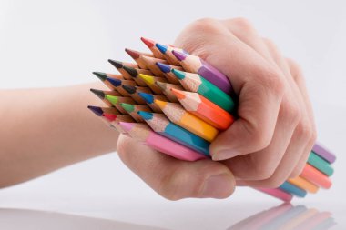 Beyaz arkaplanda el ele tutuşan renkli kalemler