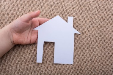 Tuvalin arka planında bir bez evi tutan el.