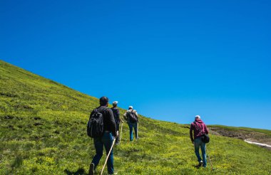 Sırt çantalı yürüyüşçüler ve yürüyüş direkleriyle Türk dağlarında yürüyorlar