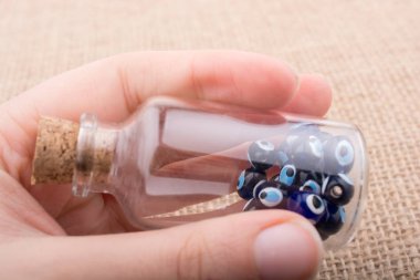 Hatıra olarak şişede nazar boncuğu tutan el.