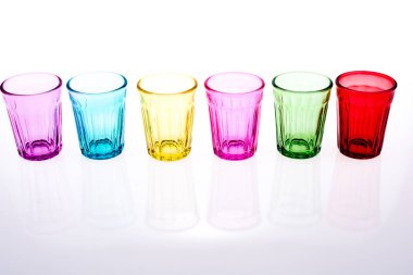 Beyaz arka plana dizilmiş renkli içki bardakları