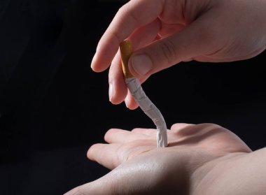 El siyah arka planda sigara kırıyor.