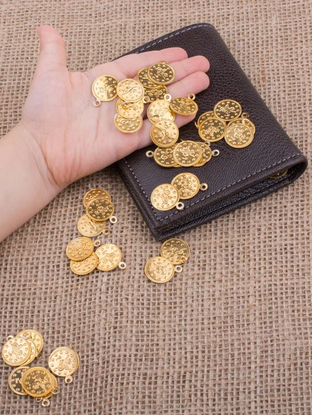 Wallet and plenty of fake gold coins in hnad